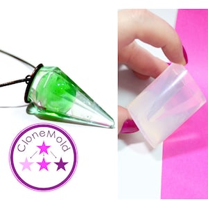Puede incluir: Un collar con colgante transparente en forma de cono con un interior verde moteado. El colgante está suspendido de un cordón negro. Se sostiene un molde de silicona en la mano. El logotipo "CloneMold" está en la esquina inferior izquierda.