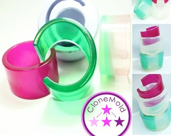 May include: A set of four clear resin rings with different color combinations. The rings are open on one side and have a rounded shape. The colors include pink, green, and white. The rings are stacked on top of each other and are arranged in a circle. The image also includes a logo with the text "Clone Mold" and three stars in pink, white, and purple.