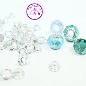 May include: A close-up of silver metal eyelets and three faceted glass beads. The beads are light blue, turquoise, and green. The text "Clone Mold" is visible in the top center of the image.
