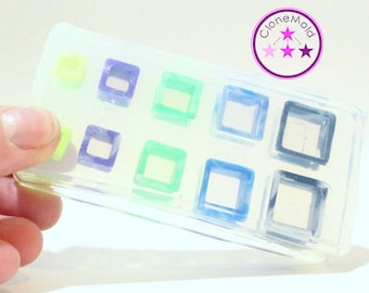 May include: A clear silicone mold with eight square cavities. The cavities are outlined in different colors, including green, blue, and purple.