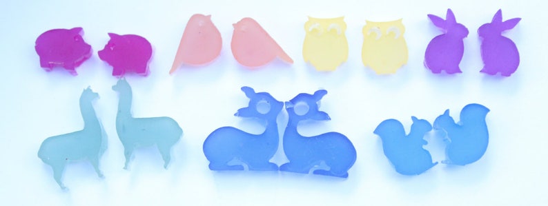 May include: A collection of colorful animal-shaped resin charms. The charms include pigs, birds, owls, rabbits, llamas, deer, and squirrels. The charms are in shades of pink, orange, yellow, purple, blue, and teal.