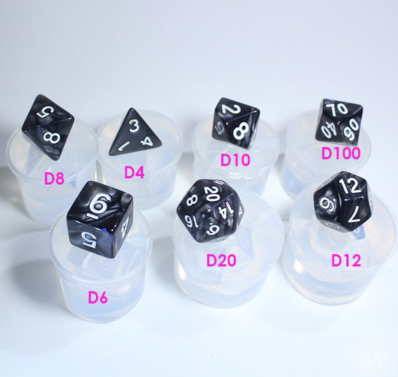 May include: A set of ten black and white dice in various shapes and sizes, including a D4, D6, D8, D10, D12, and D20. Each die is sitting in a clear plastic mold.