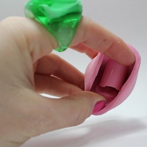 K&ouml;nnte beinhalten: Eine rosa Silikonform mit einem hohlen Zentrum, die f&uuml;r die Herstellung von Kerzen oder Seife konzipiert ist. Die Form ist offen und zeigt das Innere, das eine zylindrische Form hat.