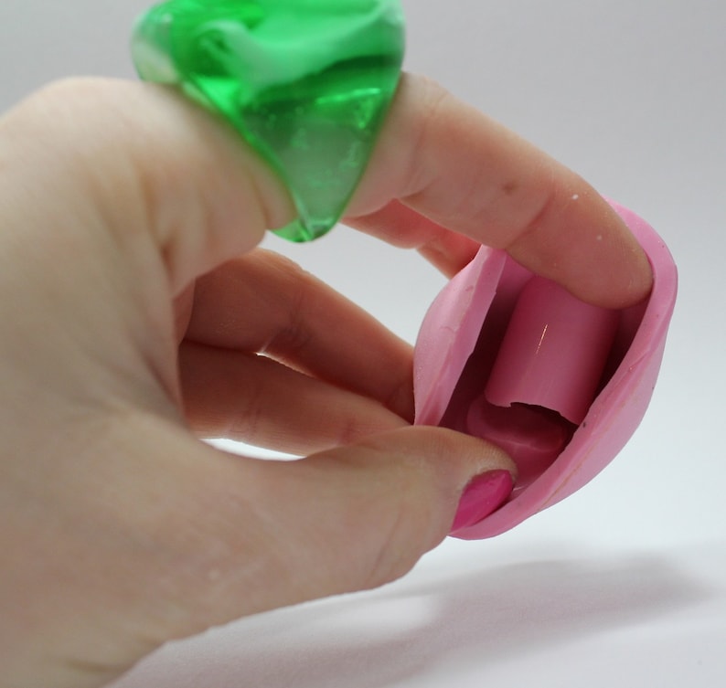K&ouml;nnte beinhalten: Eine rosa Silikonform mit einem hohlen Zentrum, die f&uuml;r die Herstellung von Kerzen oder Seife konzipiert ist. Die Form ist offen und zeigt das Innere, das eine zylindrische Form hat.