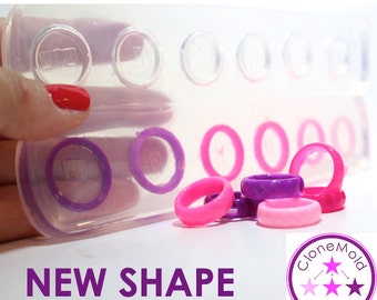 May include: A clear silicone mold with eight ring-shaped cavities. The mold is filled with purple and pink rings. The text "NEW SHAPE" is printed below the mold. A purple circle with the text "Clone Mold" and three white stars is in the lower right corner of the image.