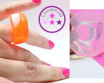 May include: An orange, rectangular ring is worn on a finger with bright pink nail polish. The ring is made of a translucent material. The image also shows a clear mold of the ring and the "CloneMold" logo.