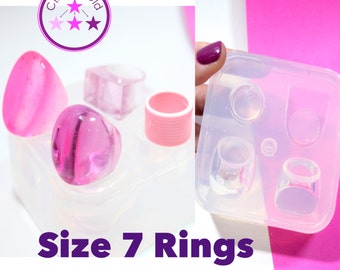 May include: A clear silicone mold for making size 7 rings. The mold has four cavities, including a round, oval, and two square shapes. The mold is shown with pink resin rings.