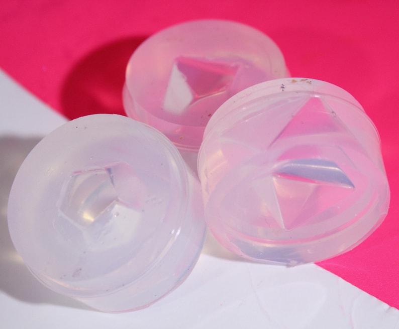 May include: Three clear silicone molds with a raised diamond shape in the center. The molds are round and have a smooth, glossy finish.