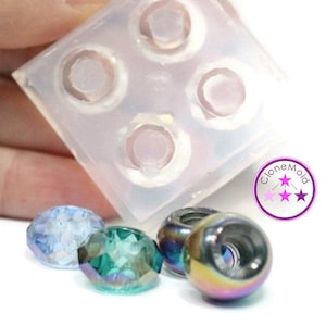 May include: A clear silicone mould with four circular cavities, next to several faceted beads in iridescent and metallic finishes. The beads are in shades of blue, green, and rainbow hues. The image includes a logo with the text "CloneMold".
