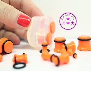 May include: A set of orange acrylic ear gauges with black o-rings. The gauges come in a variety of sizes and are packaged in a clear plastic container. The container has the text "Clone Mold" printed on it.
