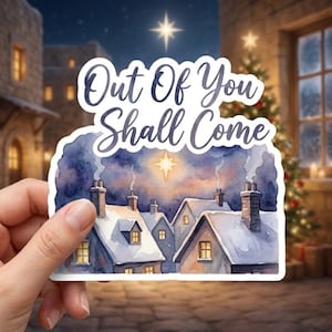 May include: A die-cut sticker featuring a watercolor illustration of a snowy village at night with glowing windows and chimneys under a bright star. The text "Out Of You Shall Come" is printed in dark blue script at the top of the sticker design.