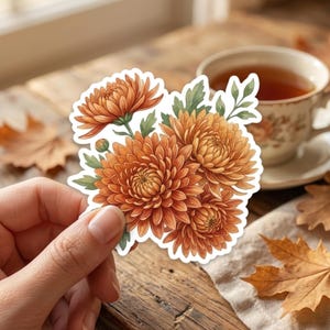 May include: A die-cut sticker featuring a cluster of vibrant orange chrysanthemum flowers with green leaves and a small bud. The illustration displays detailed petals in varying shades of orange, arranged in a dense, rounded floral bouquet shape.