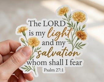 Puede incluir: Una pegatina troquelada con flores de caléndula amarillas y tallos verdes que rodean el texto: The LORD is my light and my salvation whom shall I fear Psalm 27:1. Las letras combinan una fuente serif gris oscuro y una caligrafía marrón dorada.