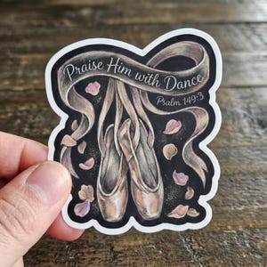 May include: A sticker featuring a pair of ballet pointe shoes with ribbons, surrounded by pink and brown petals. The text "Praise Him with Dance" and "Psalm 149:3" are written on a ribbon against a black background.