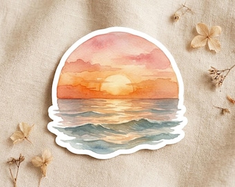 Könnte beinhalten: Ein gestanzter Aufkleber mit einem Aquarellbild eines Sonnenuntergangs über dem Ozean. Die Szene zeigt eine leuchtend gelbe Sonne, orangefarbene und rosafarbene Wolken sowie bläuliche Wellen, die das Licht reflektieren, mit weißem Rand.