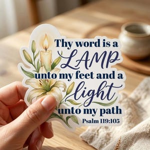 May include: A sticker with the text "Thy word is a LAMP unto my feet and a light unto my path Psalm 119:105." The sticker features a lit candle, white lilies, and green leaves. The text is in a dark blue script font.