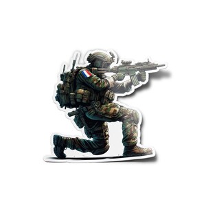Peut inclure: Un soldat en tenue de camouflage agenouillé et visant un fusil avec une lunette. Le soldat porte un casque et a un patch du drapeau français sur son épaule.