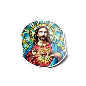 Può includere: Un adesivo con un'immagine religiosa di Gesù Cristo. L'opera raffigura Gesù con lunghi capelli castani, barba e una veste rossa e blu. Un cuore con una fiamma è sul suo petto e una vetrata è sullo sfondo.