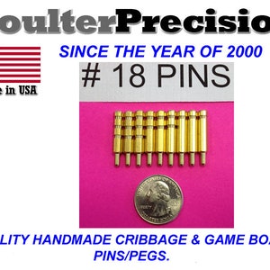 Peut inclure: Gros plan sur 18 broches métalliques dorées sur une surface rose. Les broches sont disposées en rangées et ont à peu près la taille d'une pièce de 25 cents américaine. Le texte "#18 PINS" est visible sur l'image.