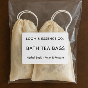 May include: Two beige bath tea bags in a clear plastic package. The bags have white drawstrings and a white label that reads "LOOM & ESSENCE CO. BATH TEA BAGS Herbal Soak • Relax & Restore."