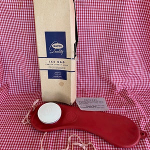 May include: A red curved ice bag with a white cap and a pink rubber band. The ice bag is on a red and white checkered surface. The box for the ice bag is in the background. The box is brown with blue text that says "Davol Quality Ice Bag Curved Throat Style." The box also has a blue label that says "Davol Inc."