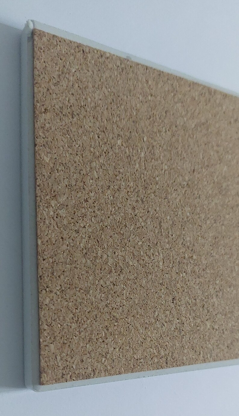 Puede incluir: Un corcho rectangular con borde blanco. El corcho tiene una superficie natural y texturizada, ideal para fijar notas o exhibir objetos. El borde blanco proporciona un borde limpio y acabado.