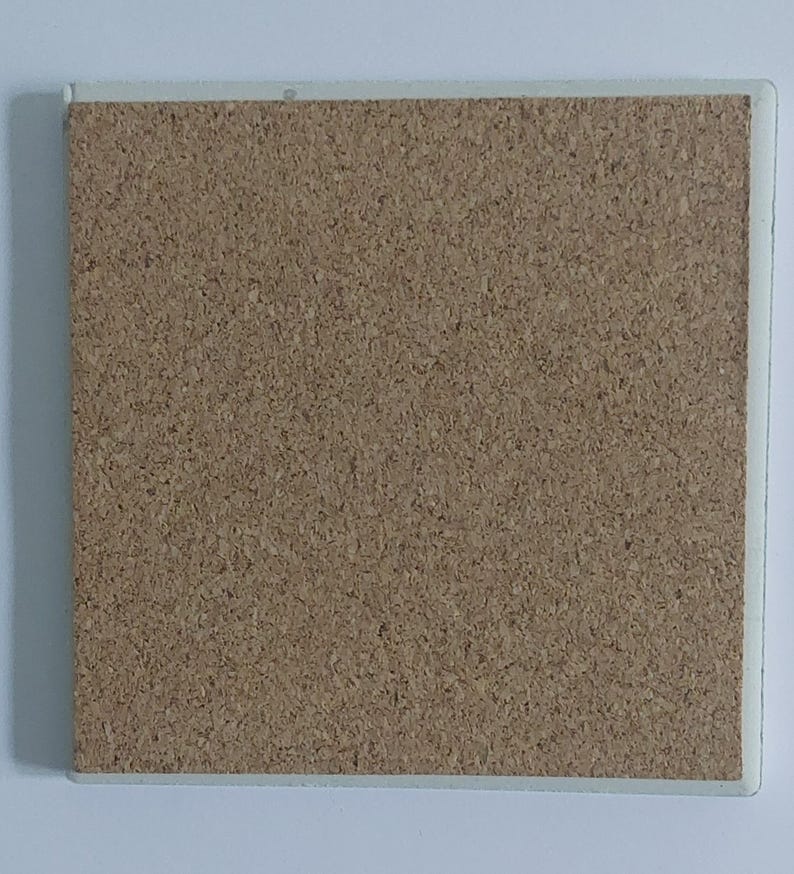 Puede incluir: Posavasos cuadrado de corcho con borde blanco. El posavasos tiene una superficie de corcho texturizado de color marr&oacute;n claro. El borde blanco proporciona un borde limpio al posavasos.