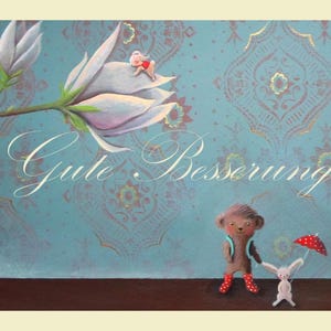 May include: An illustrated card with a teal background featuring a floral pattern and the words "Gute Besserung!" in script. A small bear and a white rabbit with a red polka dot umbrella stand on a brown surface.