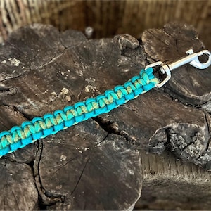 May include: A teal and green paracord keychain with a silver metal clip.