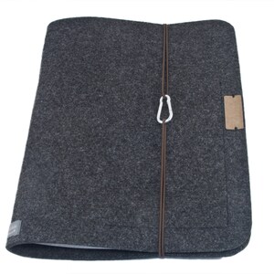 Op de afbeelding: Een grijze feltmap met een bruine band en een zilveren karabijnhaak. De map heeft een bruin leren patch aan de voorkant.