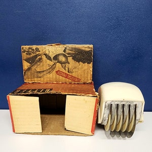 May include: Vintage white Universal Mincer food chopper with multiple blades in a red and white striped box with the words "Universal Mincer" printed on the box.