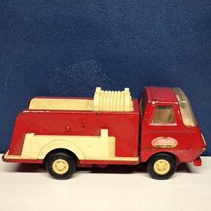May include: Red and white toy fire truck with a hose on the back. The truck has a "Tonka" logo and "Mount. Morris" text on the side.