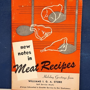 May include: Vintage cookbook cover with an orange background and white illustrations of meat cuts. The title "Meat Recipes" is in a large, stylized font. The cover also includes the text "new notes in" and "Holiday Greetings from WILLIAMS I. G. A. STORE."