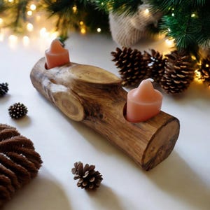 Peut inclure: Un bougeoir en bois en forme de tronc d'arbre avec deux fentes pour bougies. Le bougeoir est en bois naturel et a un aspect rustique. Deux bougies roses sont placées dans les fentes.