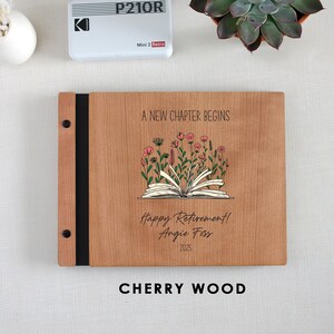 A wooden binder with a floral design and text, placed on a white surface next to a small white object and a potted plant.