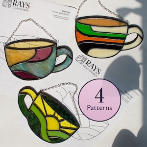 Puede incluir: Cuatro atrapasoles de taza de vidrieras en varios colores, incluyendo verde, amarillo, naranja y azul, cada uno con una cadena plateada para colgar. La imagen incluye el texto "RAYS GLASSWORKS" y "4 Patterns".