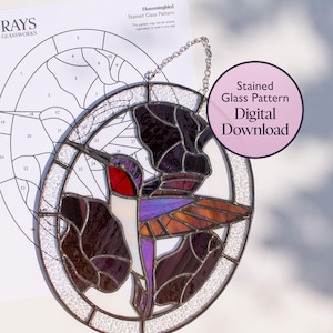 May include: A stained glass hummingbird suncatcher featuring a red throat, purple body, and dark wings, framed in an oval border. Behind it is a paper template labeled Hummingbird Stained Glass Pattern and a circular badge stating Stained Glass Pattern Digital Download.