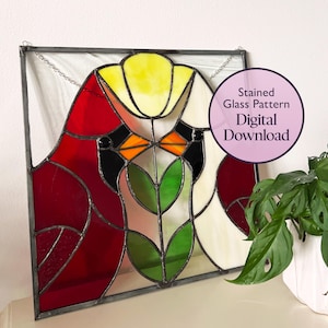 May include: A stained glass pattern digital download featuring a stylised design of two red cardinals and a yellow flower with green leaves. The pattern is framed in a black metal frame.
