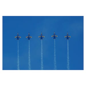 May include: Five blue and yellow fighter jets fly in formation, leaving white smoke trails against a bright blue sky.