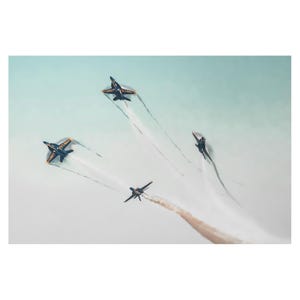 May include: Three blue and yellow fighter jets fly in formation, leaving white smoke trails against a light blue sky.