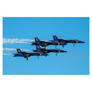 May include: Four blue and yellow fighter jets fly in formation against a clear blue sky. The jets are labeled with the numbers 1, 2, 3, and 4, and each has the words "U.S. NAVY" printed on the side.