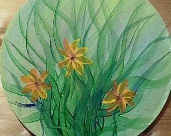 May include: A round painting on canvas with a green background and three yellow flowers. The flowers are surrounded by green leaves and stems.