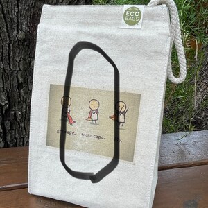 May include: A white canvas tote bag with a brown and white illustration of three stick figures wearing capes. The text "get cape. wear cape. fly." is printed below the illustration. The bag has a green logo that says "EST. 1992 ECO BAGS".
