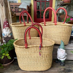 Puede incluir: Tres cestas ovaladas tejidas de paja de color claro natural. Cada cesta cuenta con dos asas resistentes y redondeadas envueltas en cuero rojo. Un asa est&aacute; adornada con una peque&ntilde;a tira colgante de cuentas de colores.