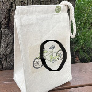 May include: A white canvas tote bag with a green bicycle illustration and the text "ECO BAGS" on a green circle.