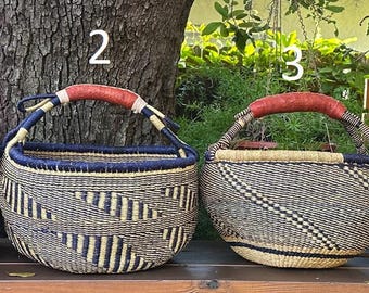 Puede incluir: Cuatro cestas tejidas etiquetadas 1, 2, 3 y 4, cada una con un cuerpo redondo, un borde azul oscuro y un asa roja envuelta. Las cestas muestran varios patrones geométricos en fibras de color tostado natural y marrón oscuro.