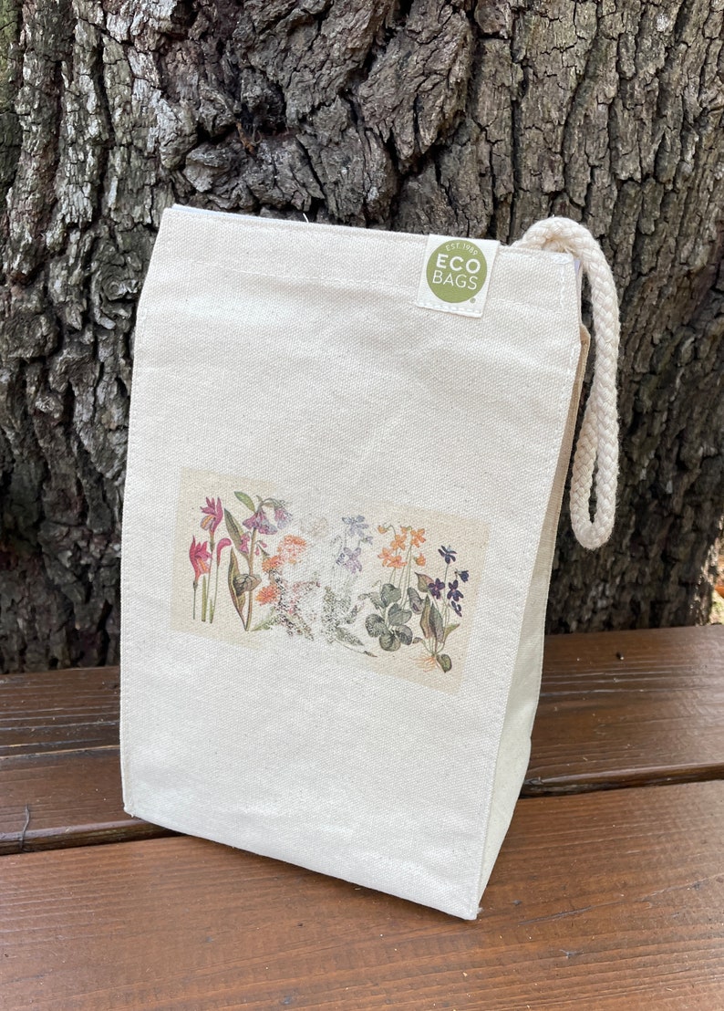 May include: A white canvas lunch bag with a floral print and a green circle logo that says "EST. 1985 ECO BAGS".