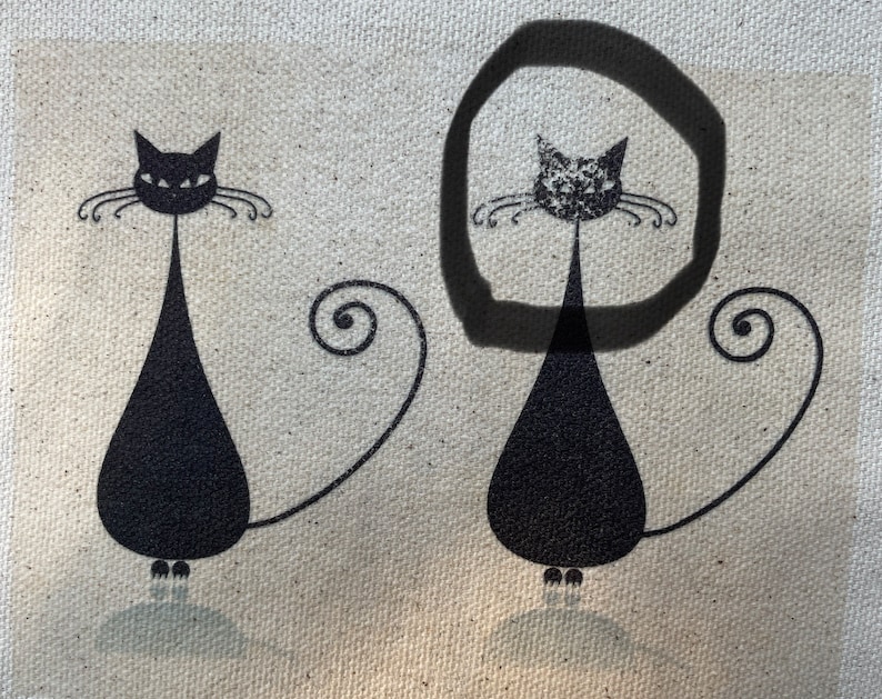 May include: Two black cat silhouettes with curled tails on a beige canvas background. The cat on the right is circled in black.