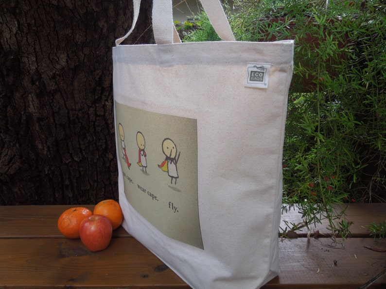 May include: White canvas tote bag with a red, yellow and blue illustration of three stick figures wearing capes. The text "wear cape... wear tape... fly." is printed on the bag.
