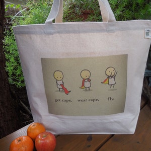 May include: A white canvas tote bag featuring a graphic of three stick figures wearing capes. The text on the bag reads "get cape. wear cape. fly."
